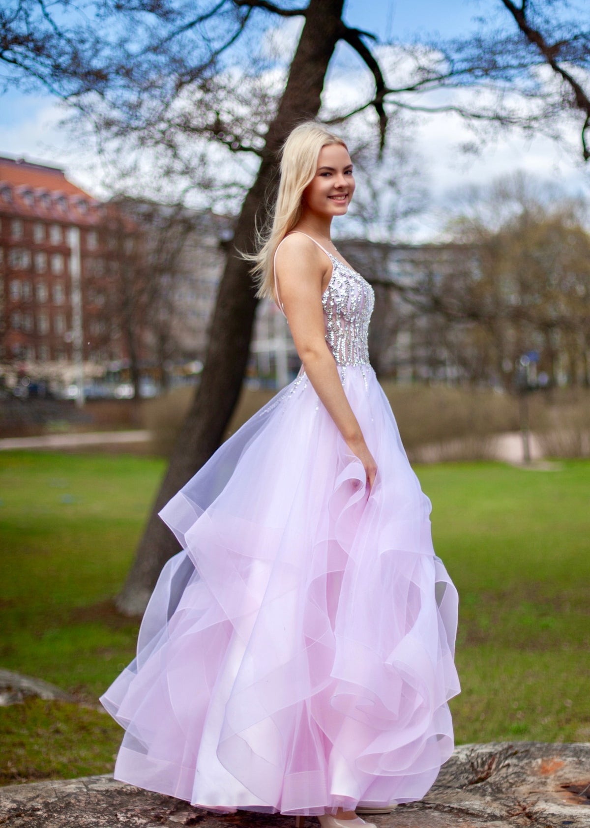 Pinkki vanhojentanssimekko kirjailtulla yläosalla ja röyhelöhelmalla, sivusta.