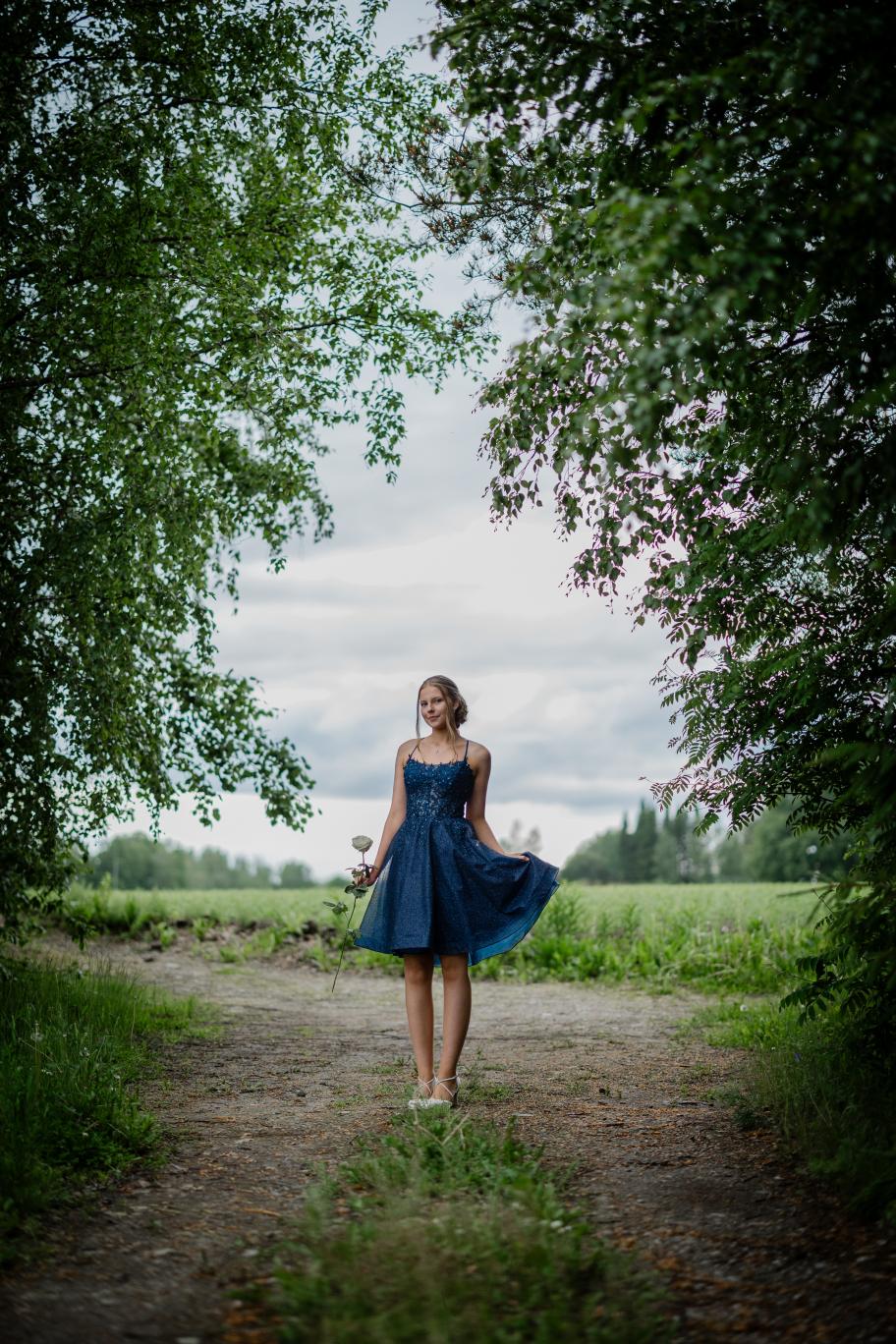 Elegantti tummansininen rippimekko kimaltavalla pinnalla ja pitsiyläosalla.