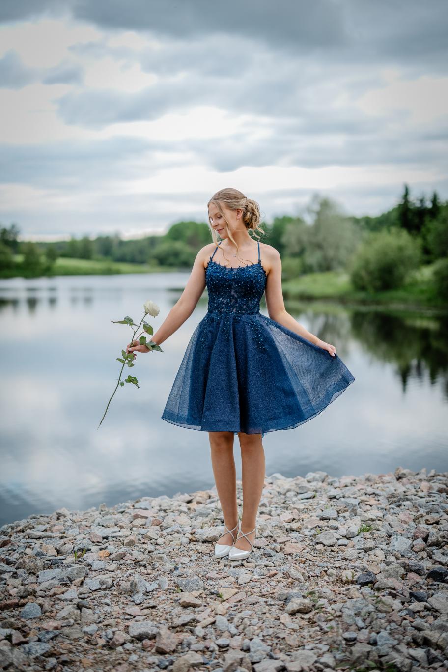 Elegantti tummansininen rippimekko kimaltavalla pinnalla ja pitsiyläosalla.