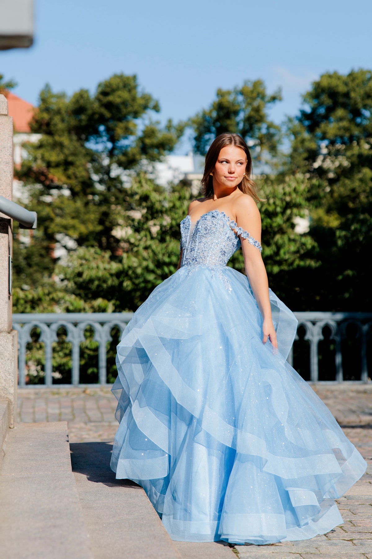 Sininen vanhojentanssimekko off shoulder -yläosalla ja röyhelöhelmalla.