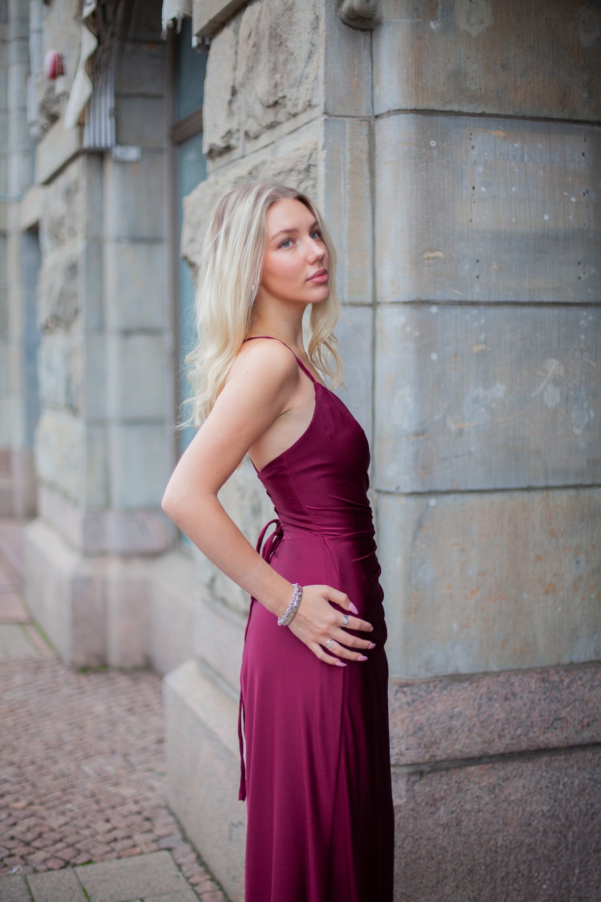 Tummanpunainen elegantti iltapuku vuosijuhliin, sivukuva.