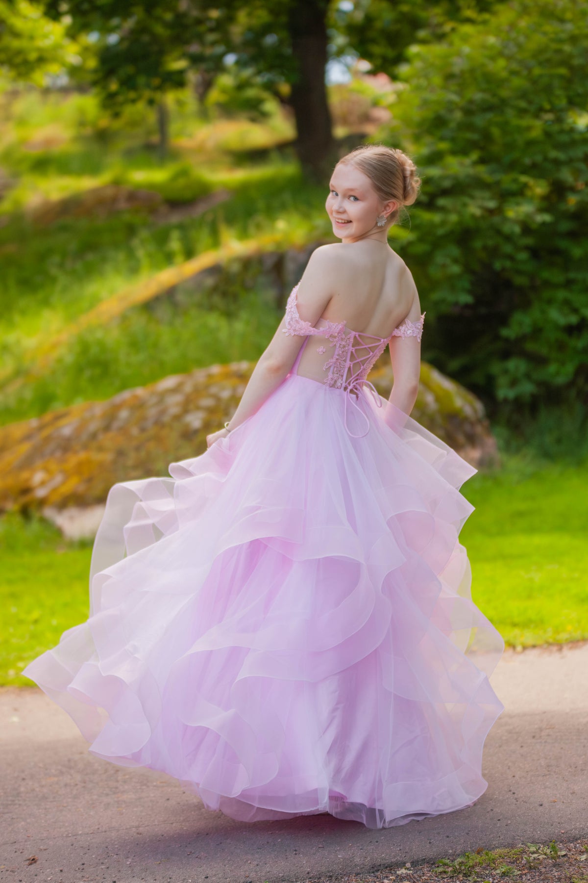 Pinkki vanhojentanssimekko off shoulder -mallilla, röyhelöhelmalla ja pitsiyksityiskohdilla.