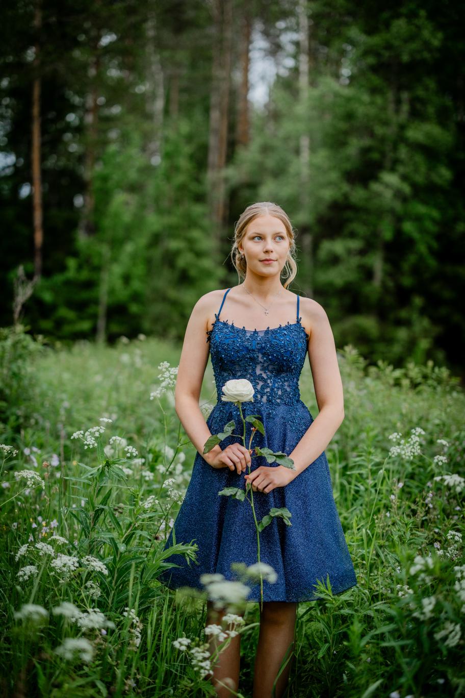 Elegantti tummansininen rippimekko kimaltavalla pinnalla ja pitsiyläosalla.