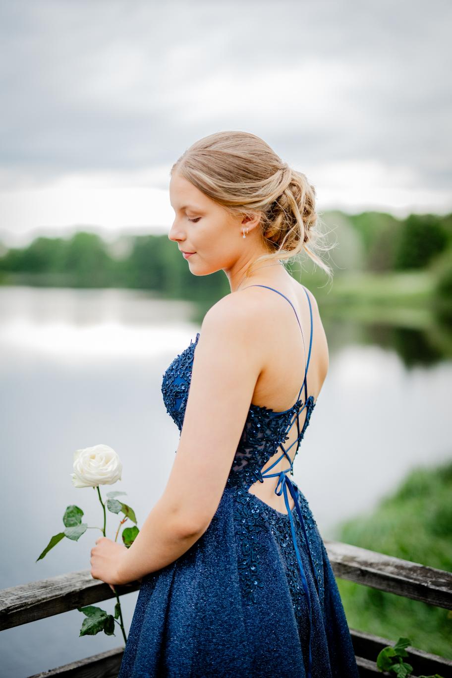 Elegantti tummansininen rippimekko kimaltavalla pinnalla ja pitsiyläosalla.