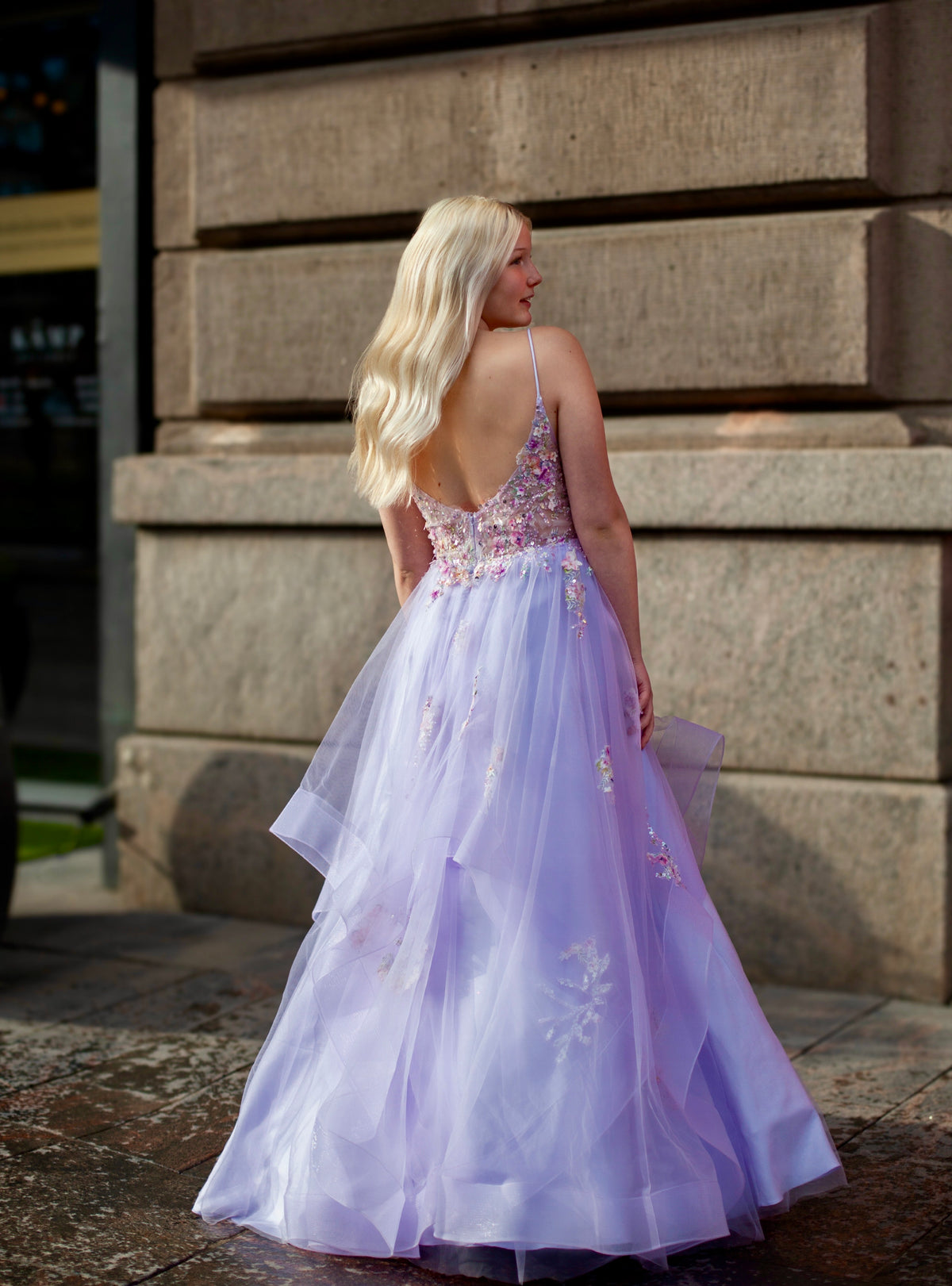 Violetti vanhojentanssimekko, kukkapitsillä ja röyhelöhelmalla, takaa.