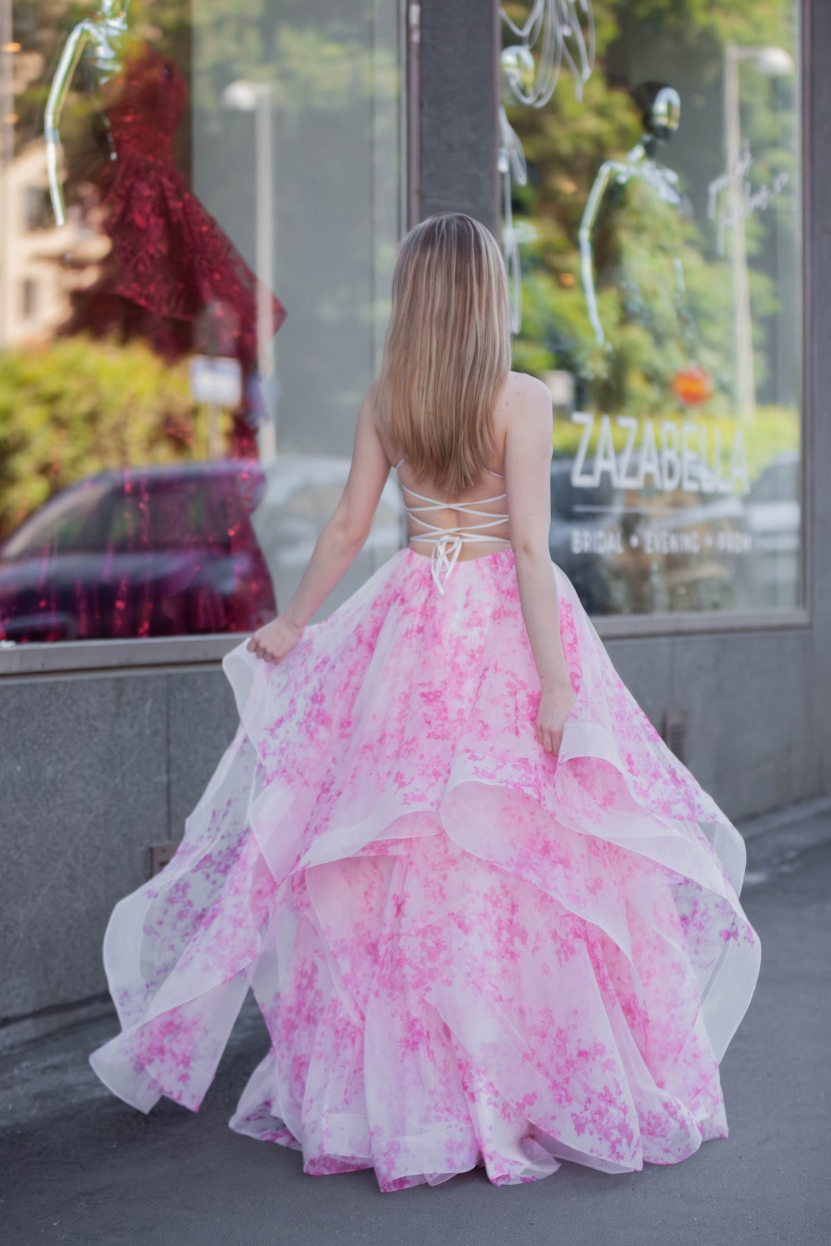 Pinkkivalkoinen vanhojentanssimekko röyhelöhelmalla ja avoimella selällä. 