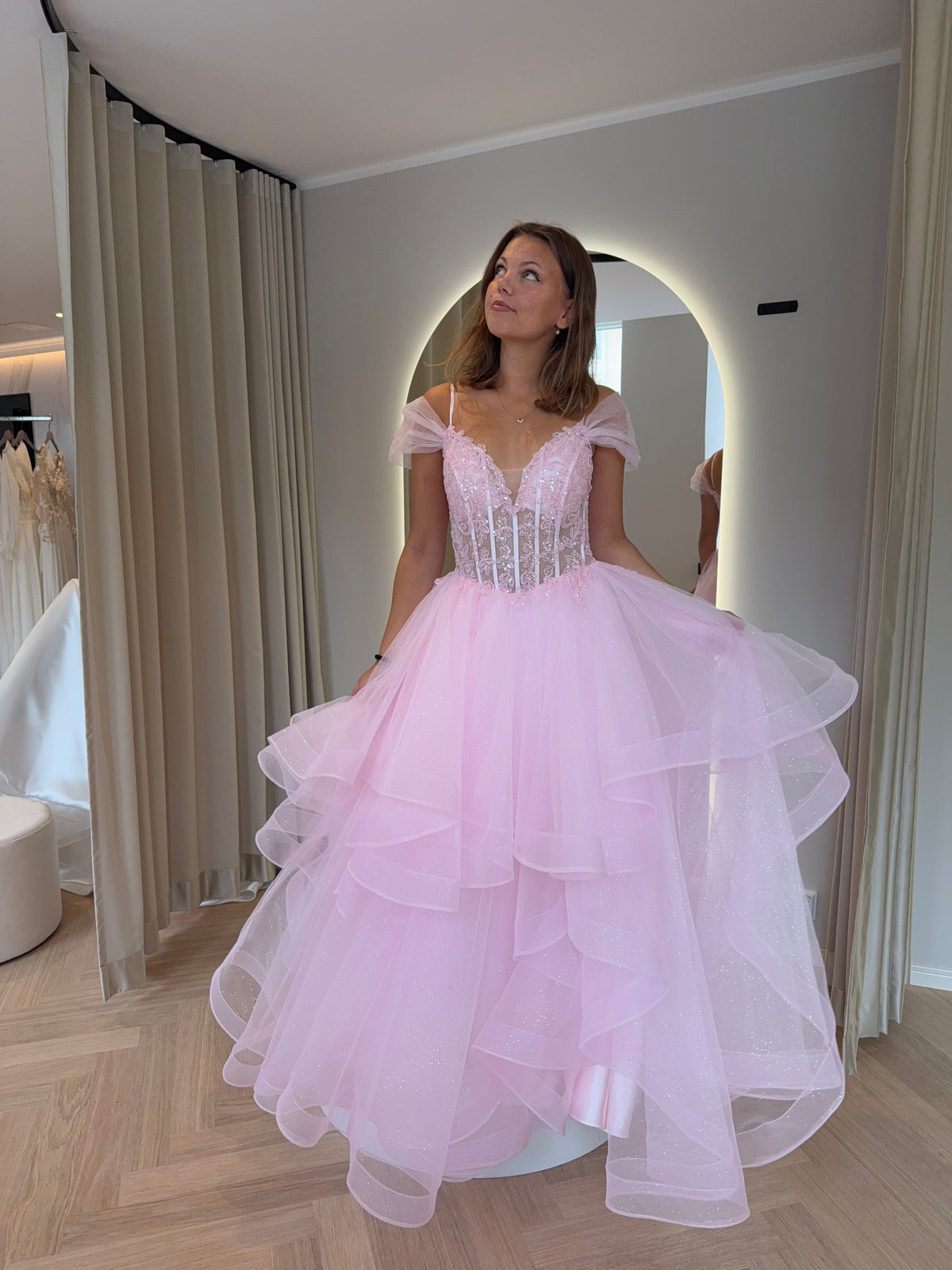 Pinkki kimaltava vanhojentanssimekko off shoulder -mallisella pitsiyläosalla ja röyhelöhelmalla.