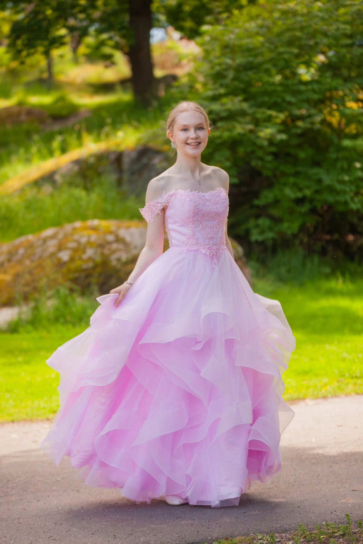 Pinkki vanhojentanssimekko off shoulder -mallilla, röyhelöhelmalla ja pitsiyksityiskohdilla.